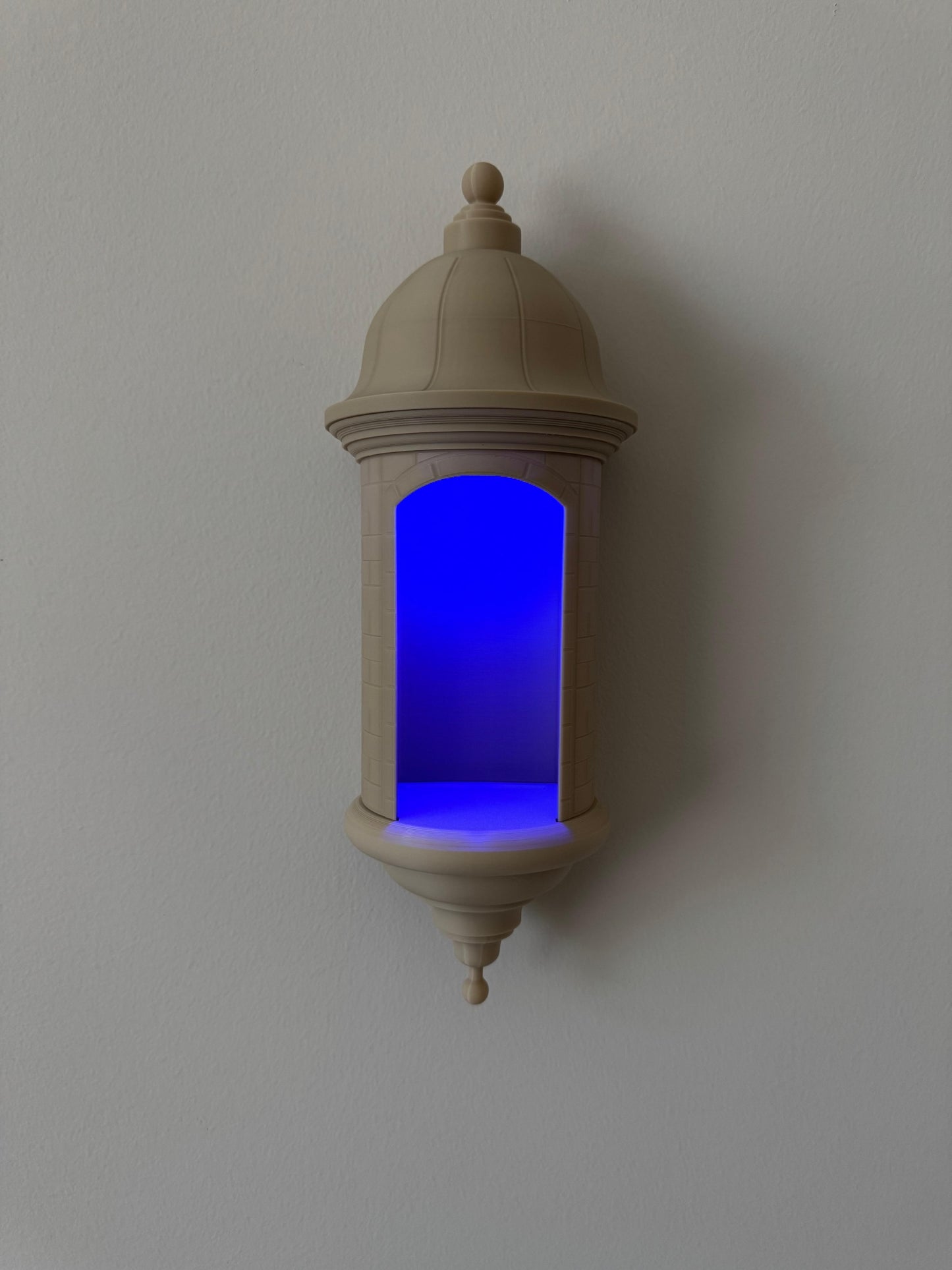 Decorative wall sconce with a blue light on a plain wall